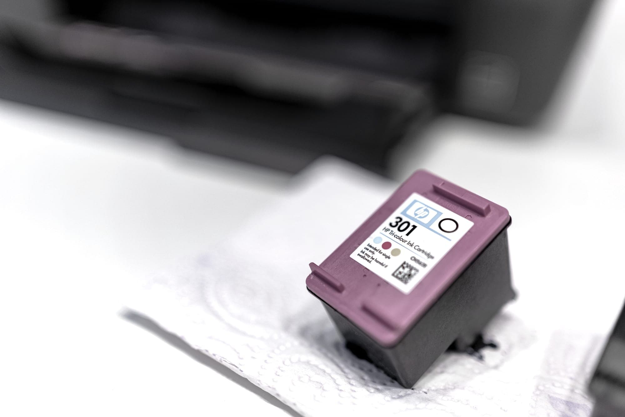 A printer ink cartridge resting on a light surface, close up