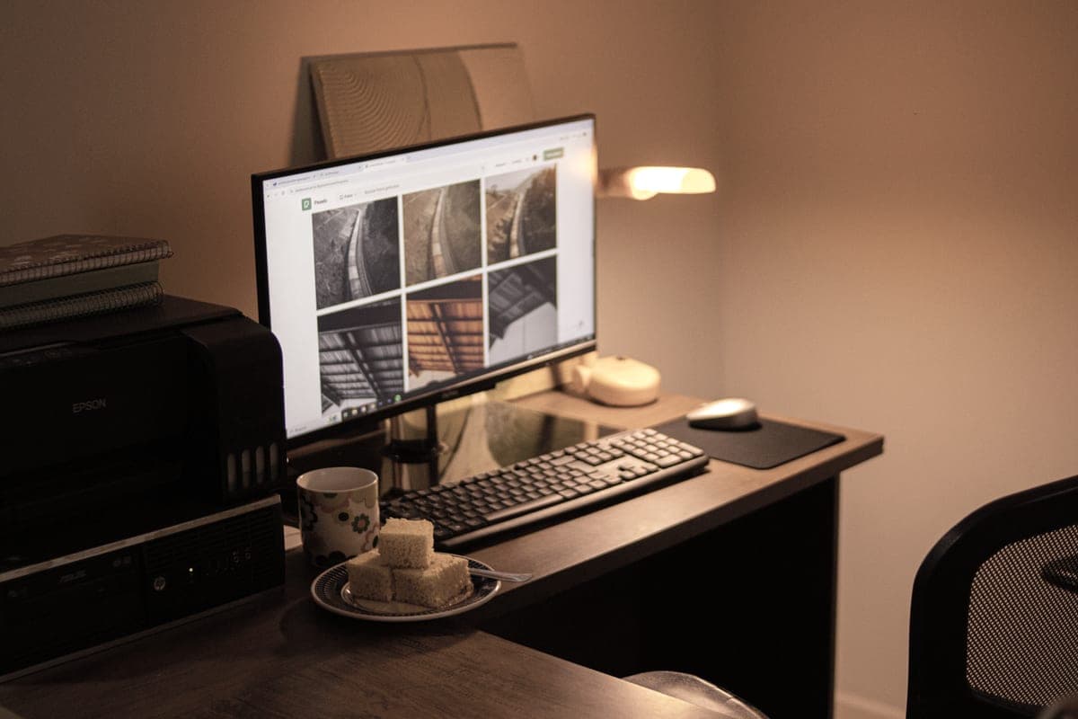 A warm-lit home office desk with a compact computer setup