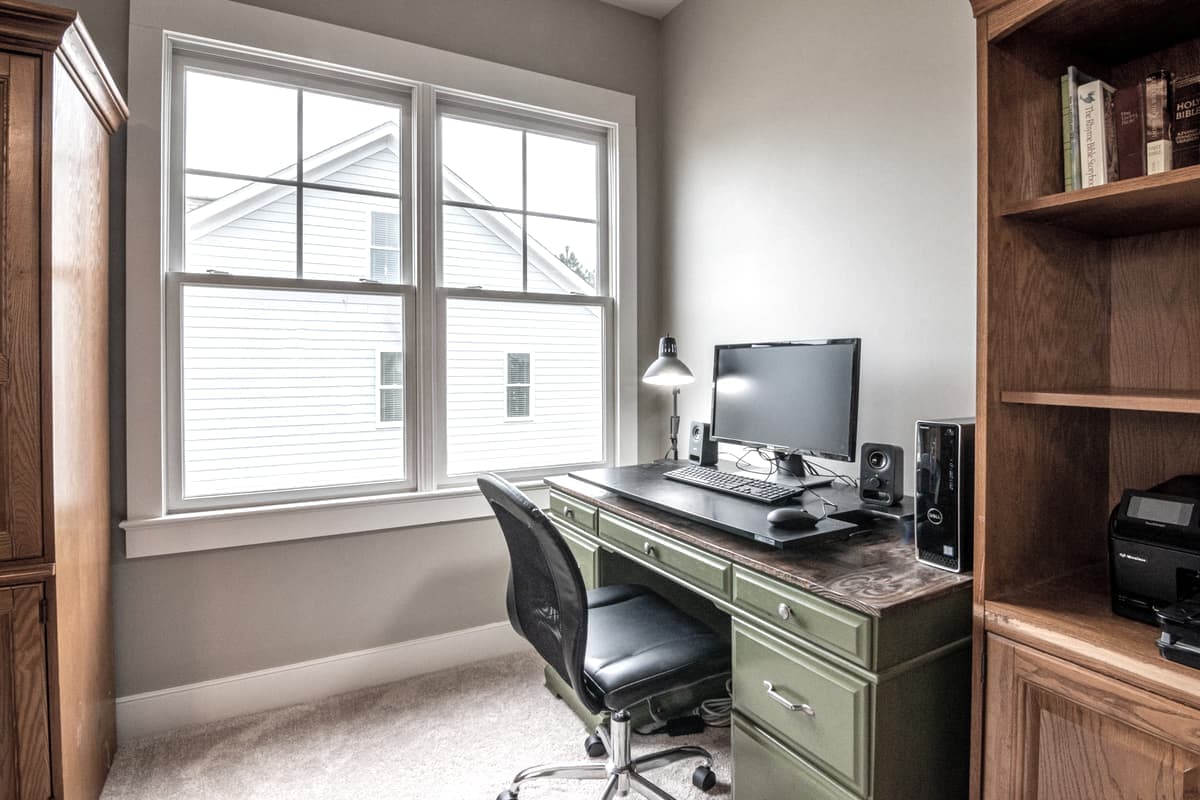 A neat home office desk with a monitor and a window behind it