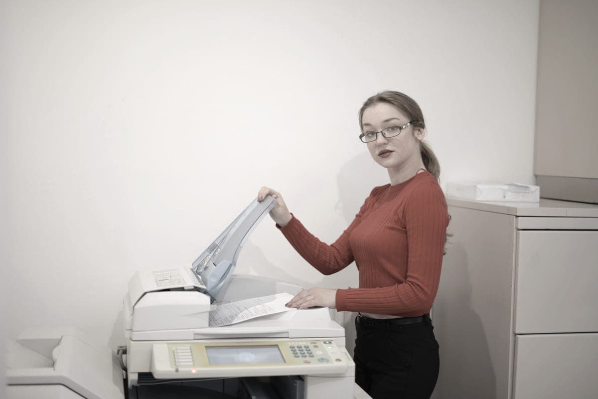 An office worker copying documents at a multifunction printer