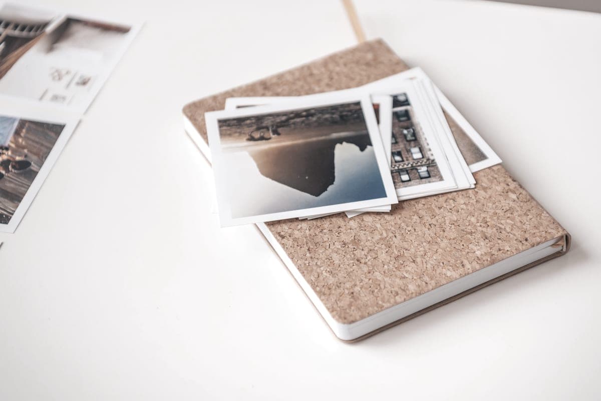 Printed photographs stacked on a notebook on a white desk