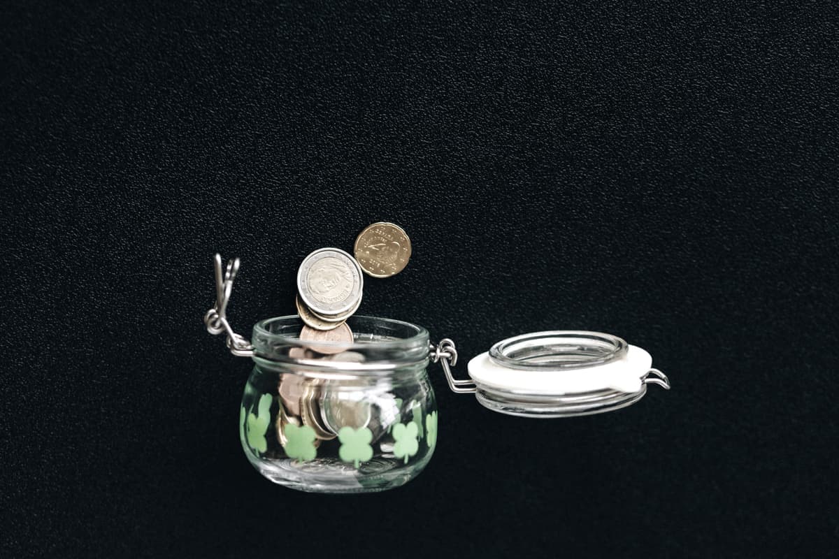 Coins falling into a glass jar, illustrating saving money