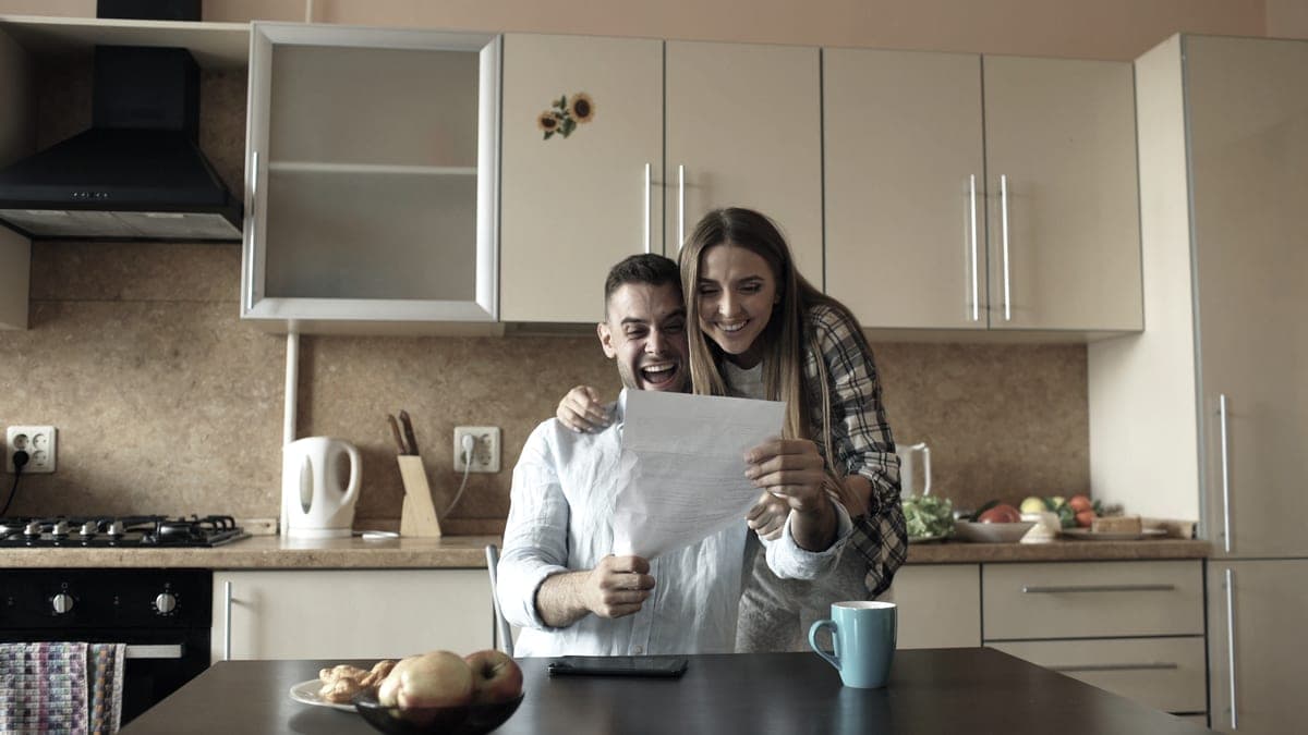 Two people at home in a kitchen, reading something together