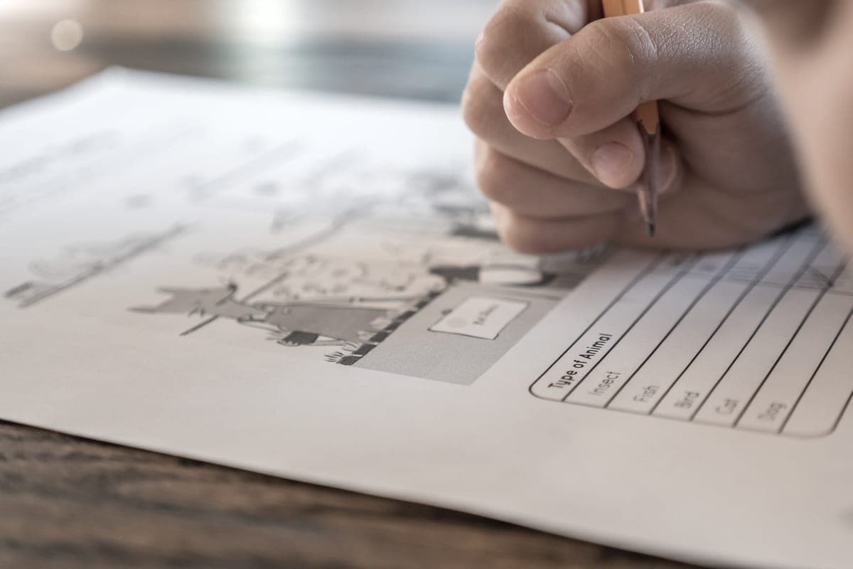 A school pupil writing on a worksheet at a desk