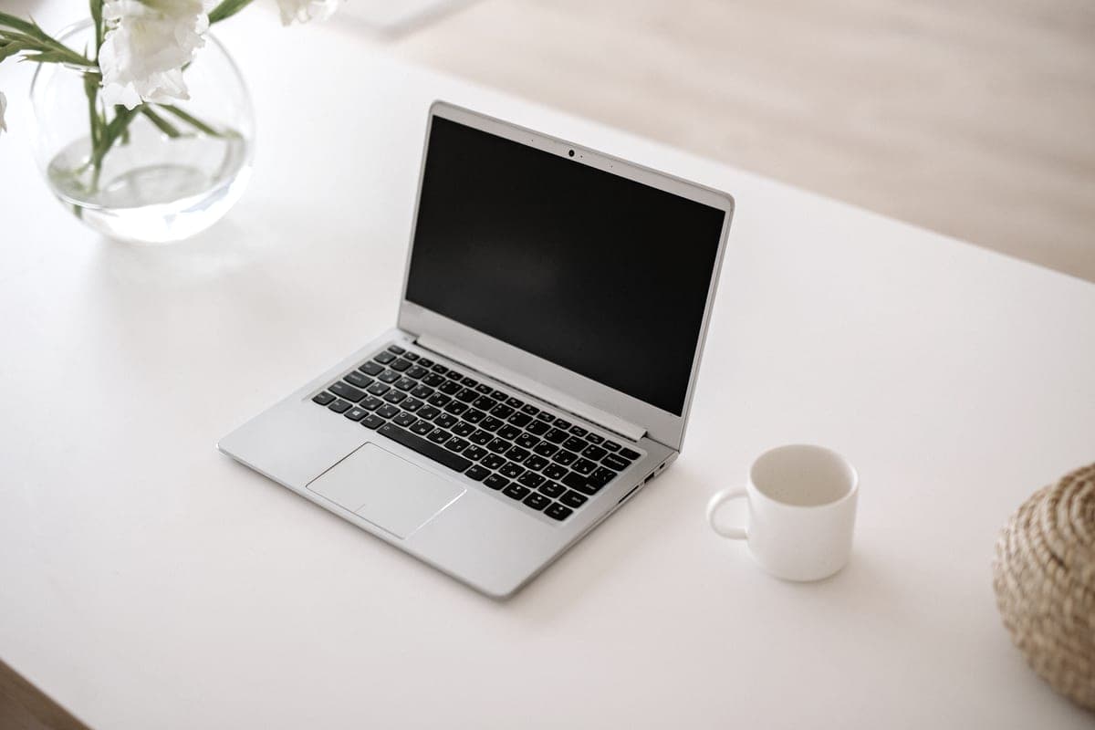 A silver laptop open on a white desk
