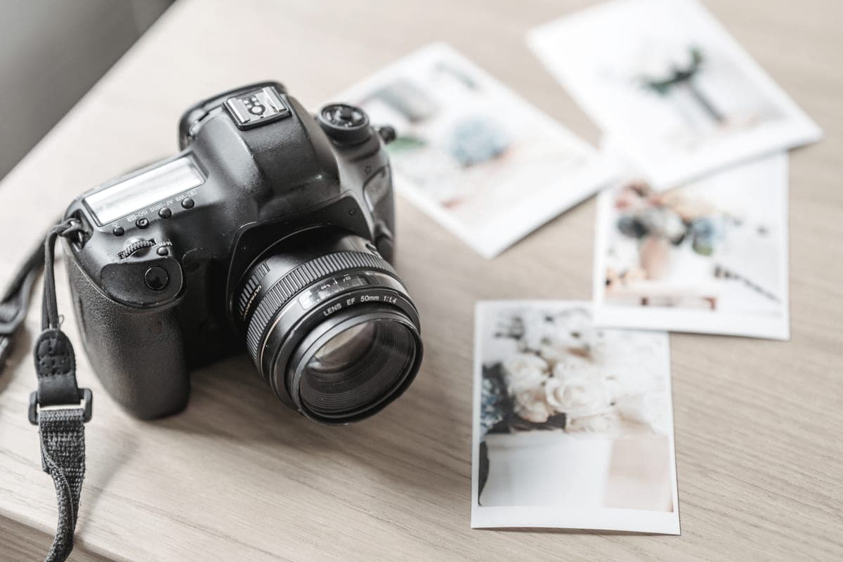 A camera on a wooden table beside printed photographs