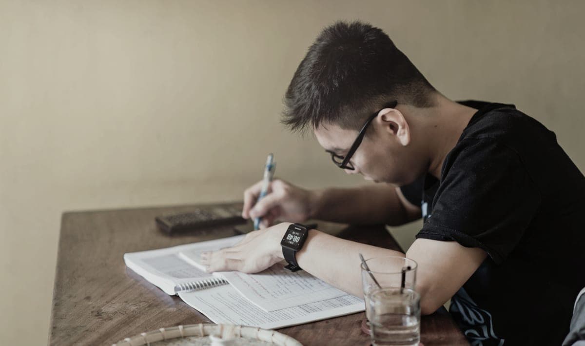 A student concentrating on studying at a desk indoors